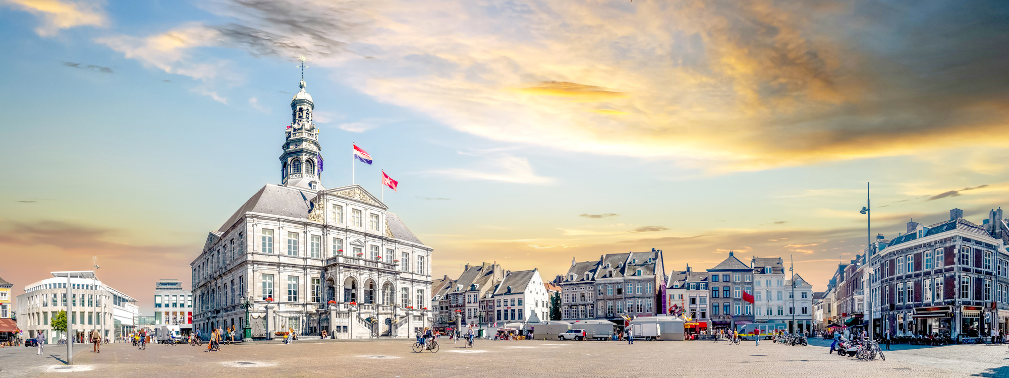 Historisches Rathaus auf einem zentralen Platz in Maastricht bei Sonnenuntergang, umgeben von klassischen und modernen Gebäuden.