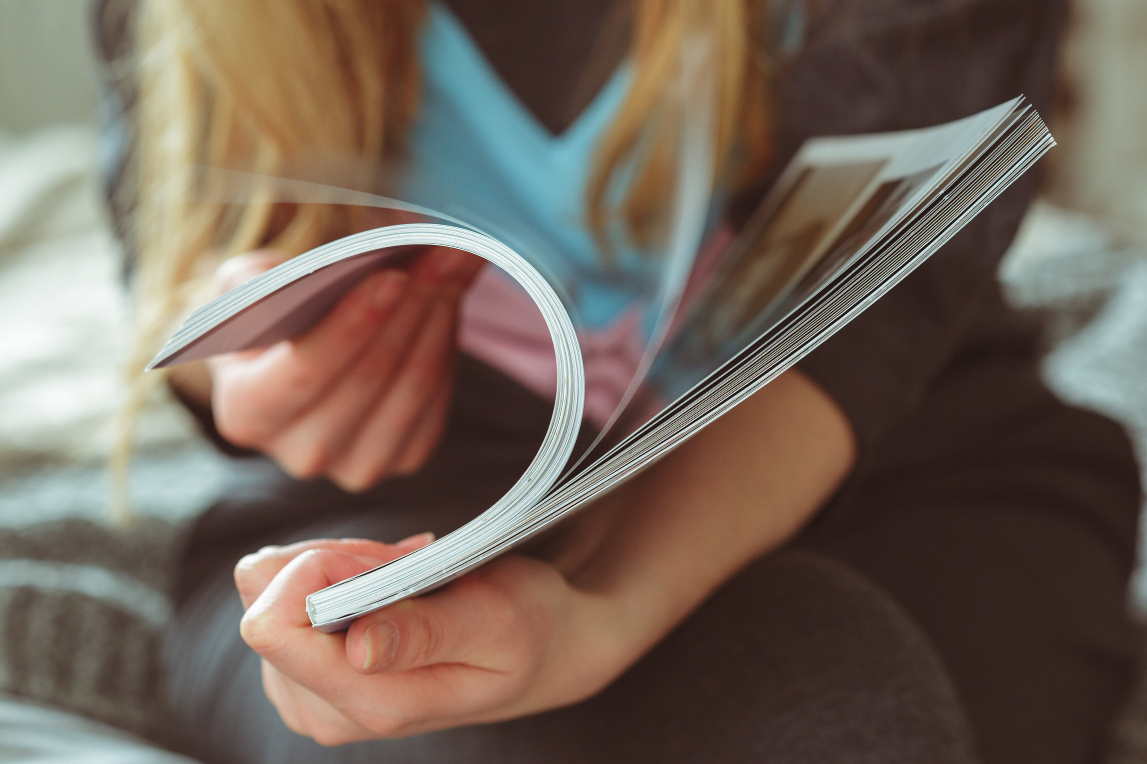 Eine Person blättert in einer Zeitschrift und betrachtet die Inhalte mit Aufmerksamkeit