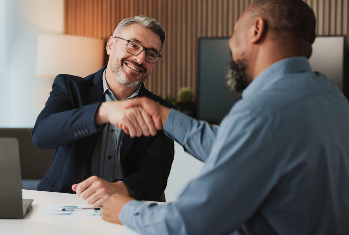 Shaking hands, agreement and business men in office for finance partnership, deal or collaboration. Happy, laptop and male financial advisor with client for investment contract with handshake