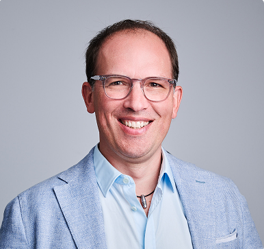 Daniel Pavonet, CEO der Pavonet GmbH, im Porträt mit hellem Sakko und Brille vor neutralem Hintergrund.