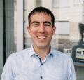 Michael Hupertz, Projektmanager bei Ficos s.a., steht lächelnd vor einem modernen Gebäude.