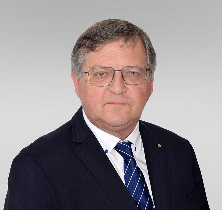 Robert Mockel, Verwaltungsratsvorsitzender der Mockel AG und Ehrenpräsident der IHK Ostbelgien, im Anzug vor grauem Hintergrund.